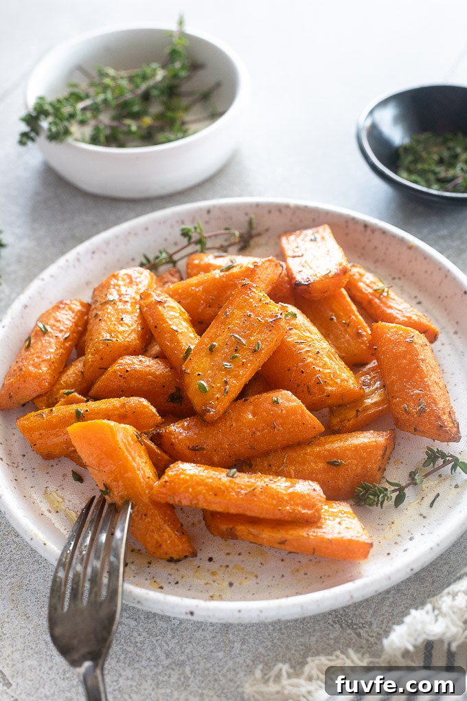 Air fryer roasted carrots on a plate with a bowl of fresh thyme behind.