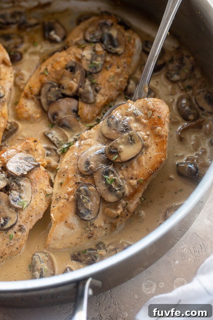 Portion of chicken marsala lifting out of the pan with a spoon.