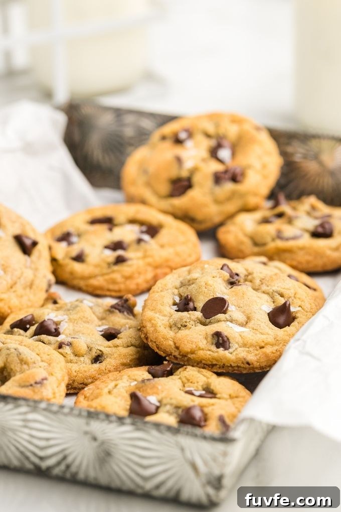 Thick and chewy chocolate chip cookies in a metal baking dish with parchment paper