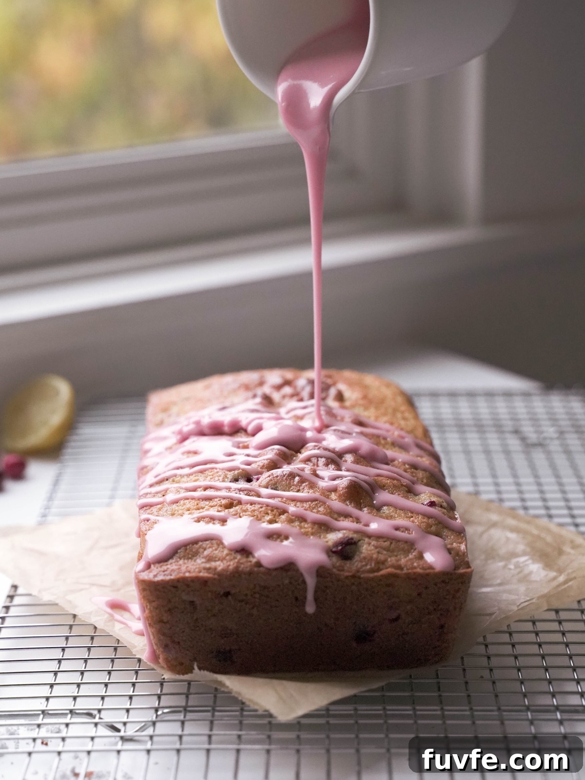 Drizzling fresh cranberry glaze onto a loaf cake