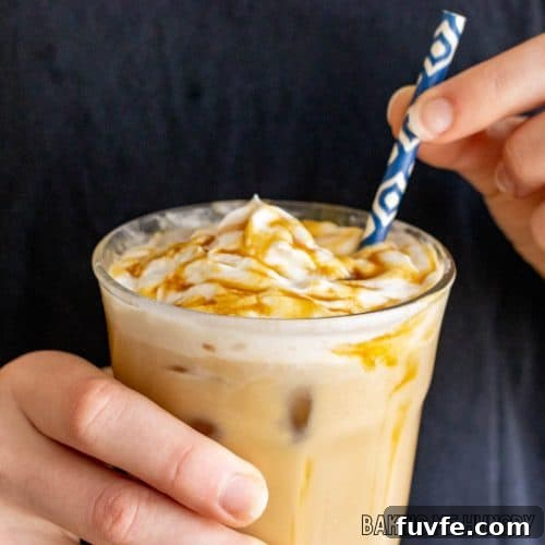 caramel iced coffee recipe in glass being held by two hands