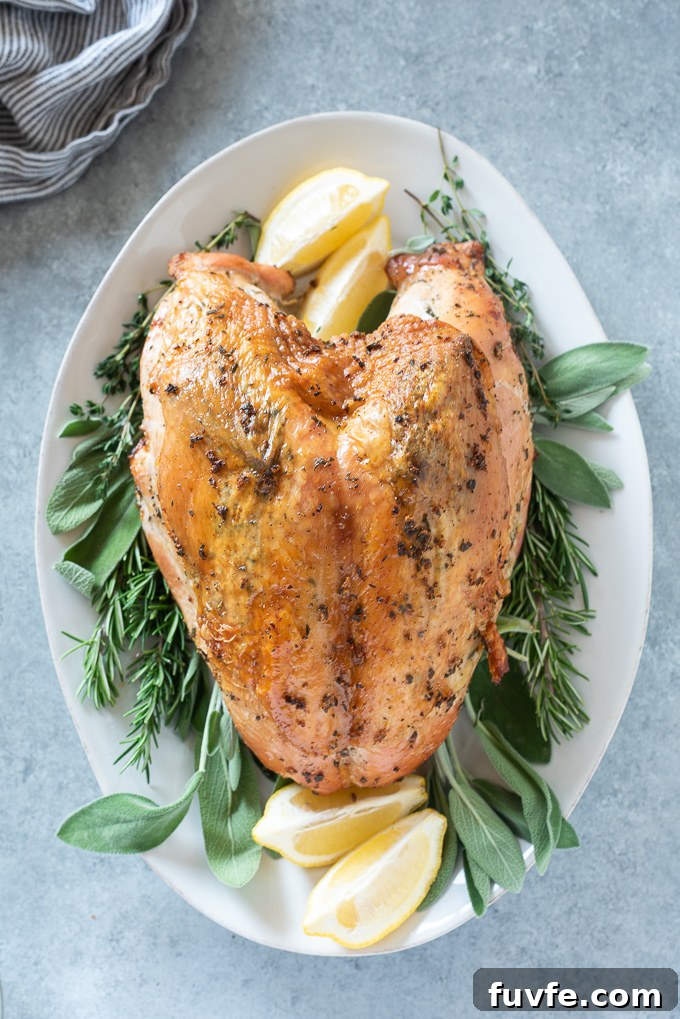 Roast turkey breast on a serving platter with herbs and lemon