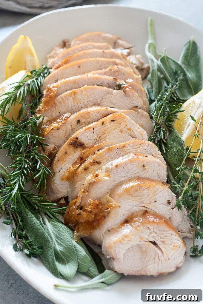 Oven roasted turkey breast sliced on a serving platter with herbs