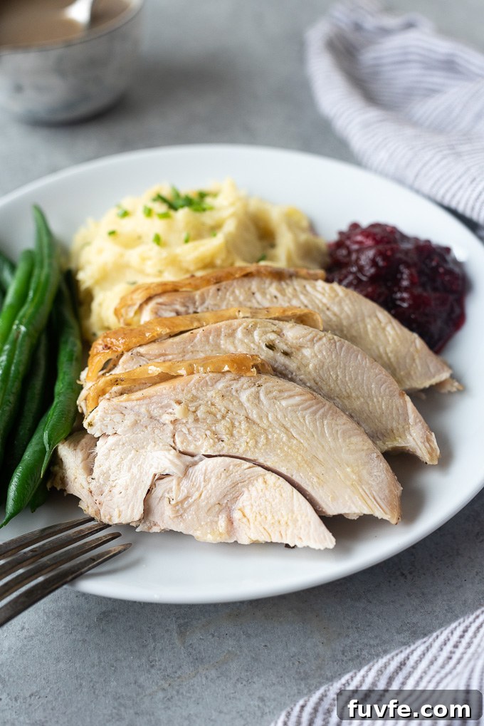 Sliced turkey breast on a plate with potatoes, cranberry sauce and green beans