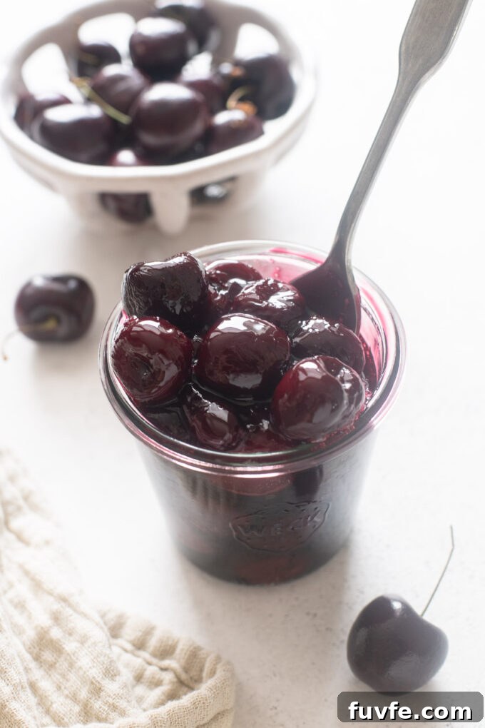 Homemade Cherry Compote Recipe for Desserts and Breakfast 3 Cherry sauce in a jar with spoon digging in.