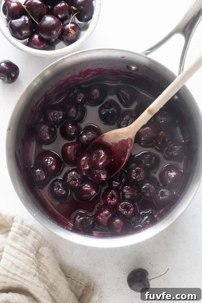 Homemade Cherry Compote Recipe for Desserts and Breakfast 5 Cherry sauce in a pot with a wooden spoon.