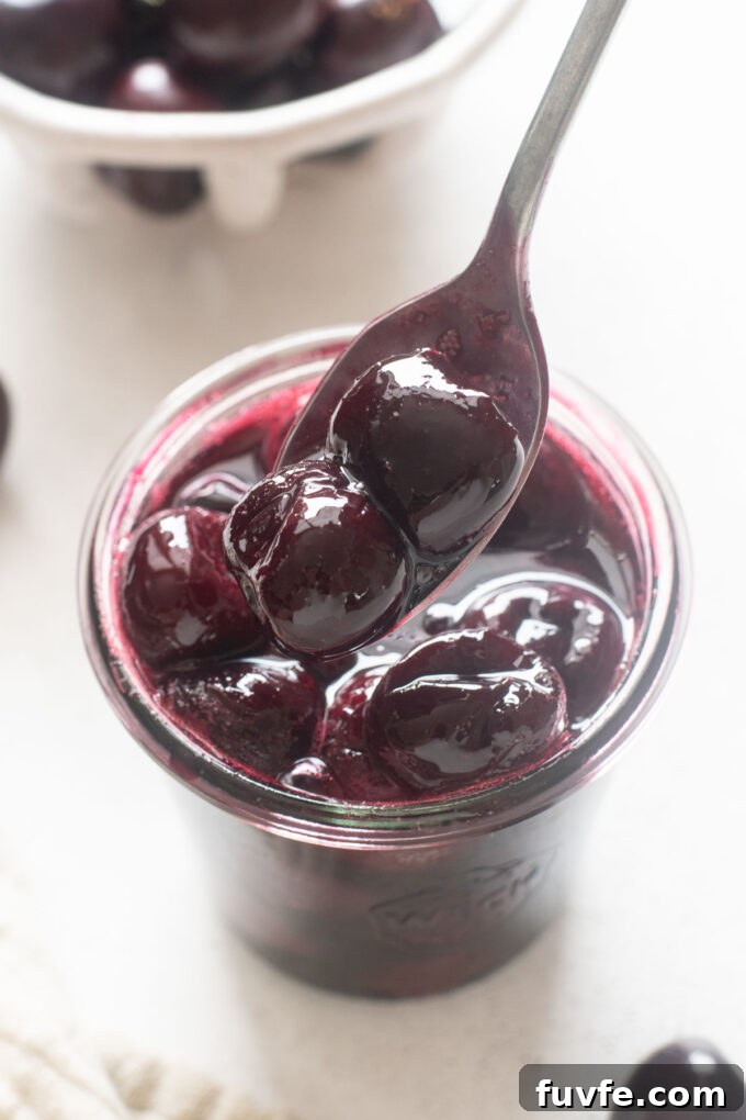 Homemade Cherry Compote Recipe for Desserts and Breakfast 6 Spoonful of cherry compote over a jar.