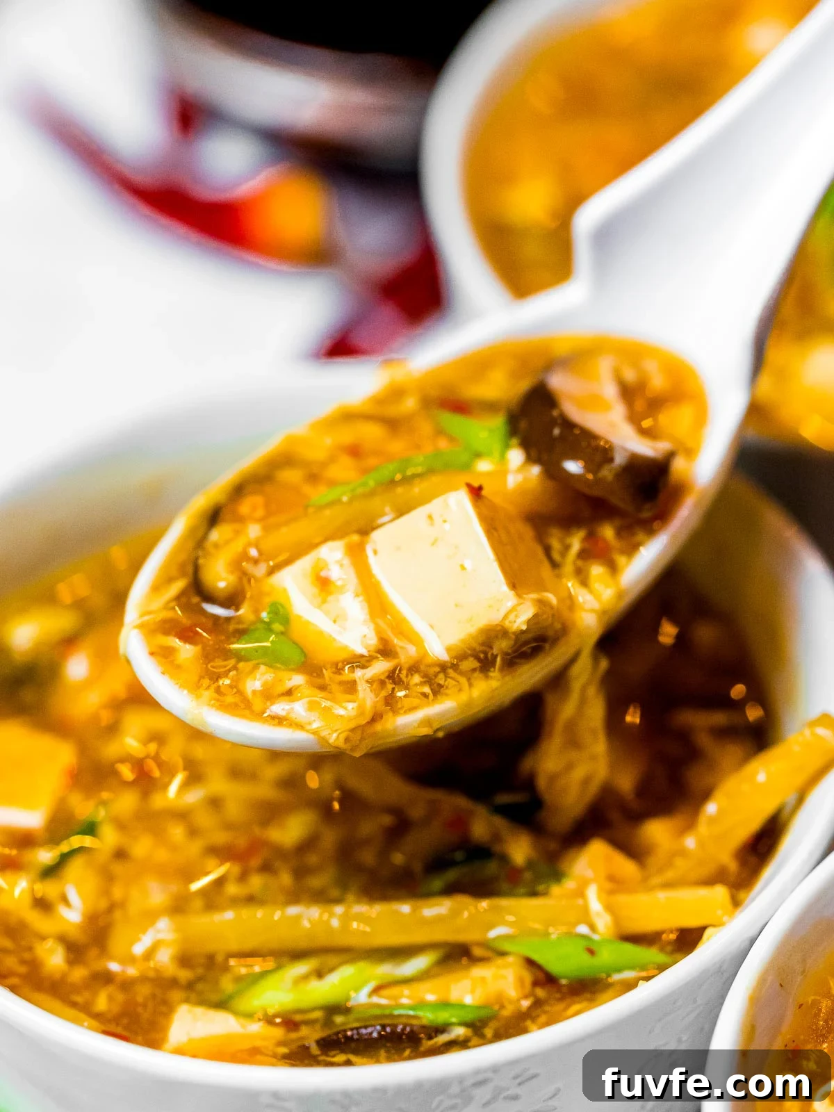 a spoonful of easy hot and sour soup with tofu, mushrooms, and bamboo shoots
