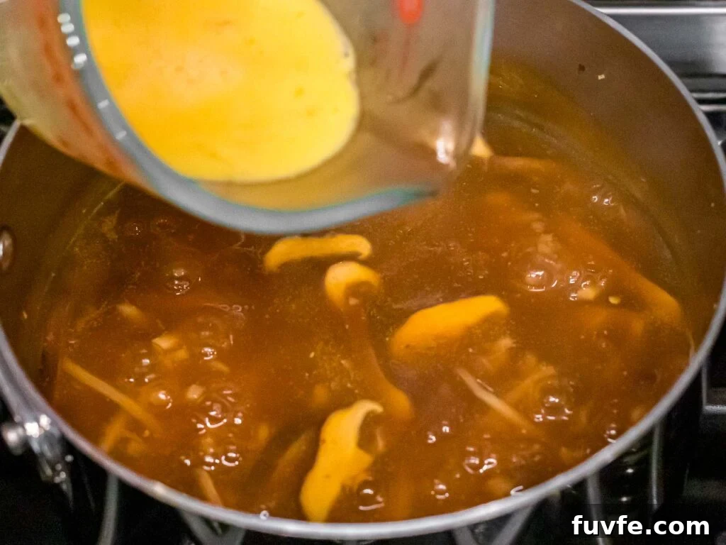 beaten eggs being added to hot and sour soup