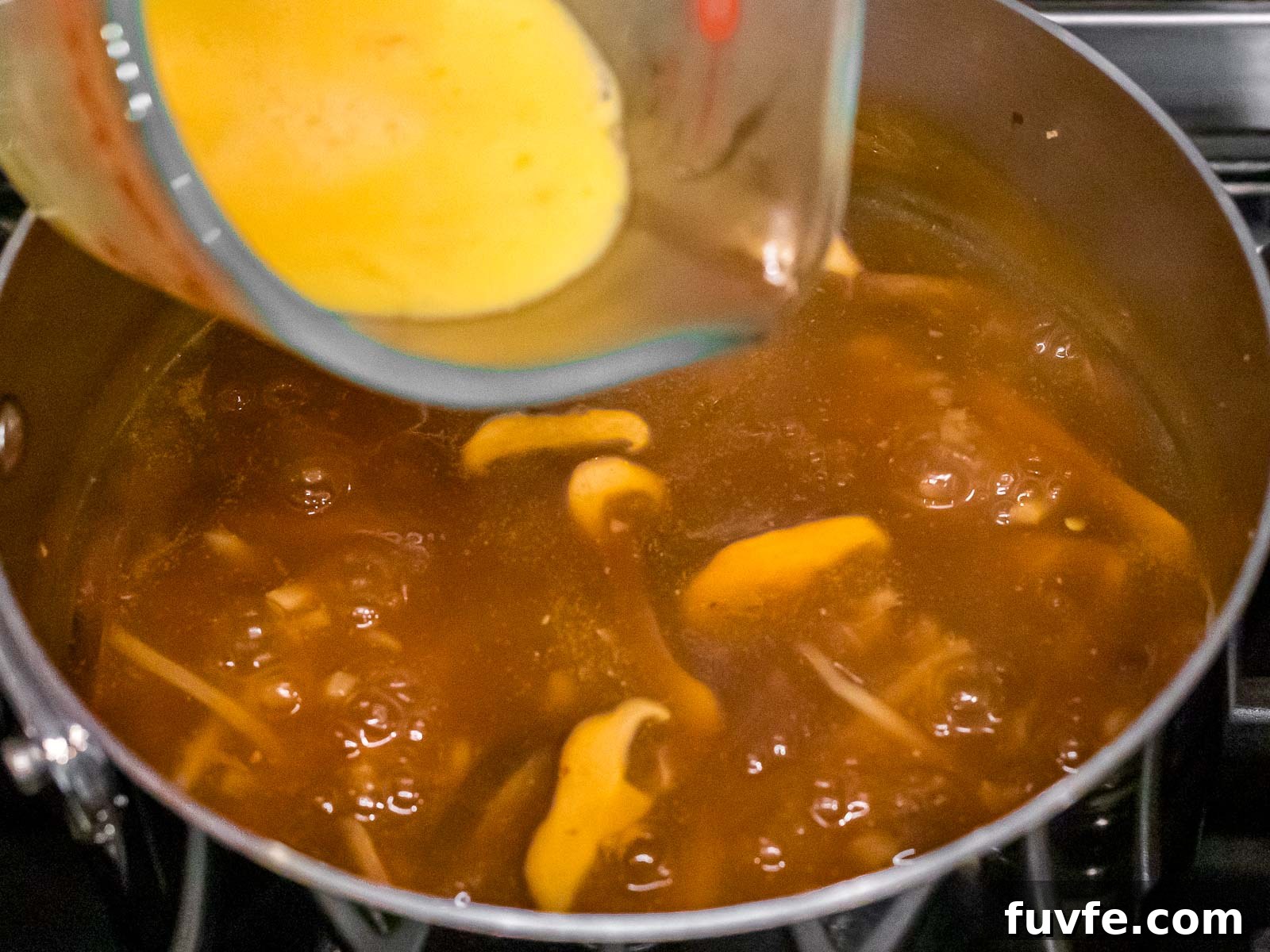 beaten eggs being added to hot and sour soup