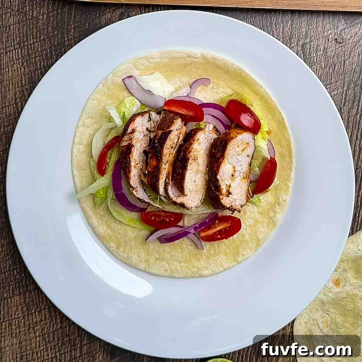 The taco toppings being added to a blackened chicken taco.