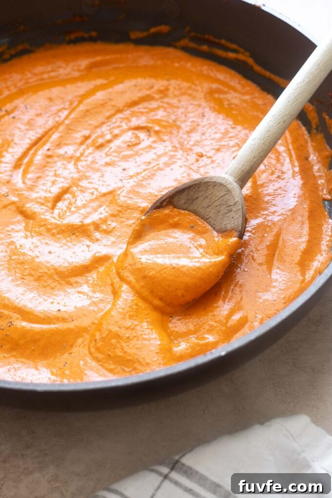 Homemade Roasted Red Pepper Sauce Recipe 5 Roasted red bell pepper sauce in a skillet with wooden spoon.