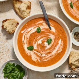 Creamy Roasted Tomato Soup Recipe with Basil 7 Creamy roasted tomato soup in a bowl with bread alongside.