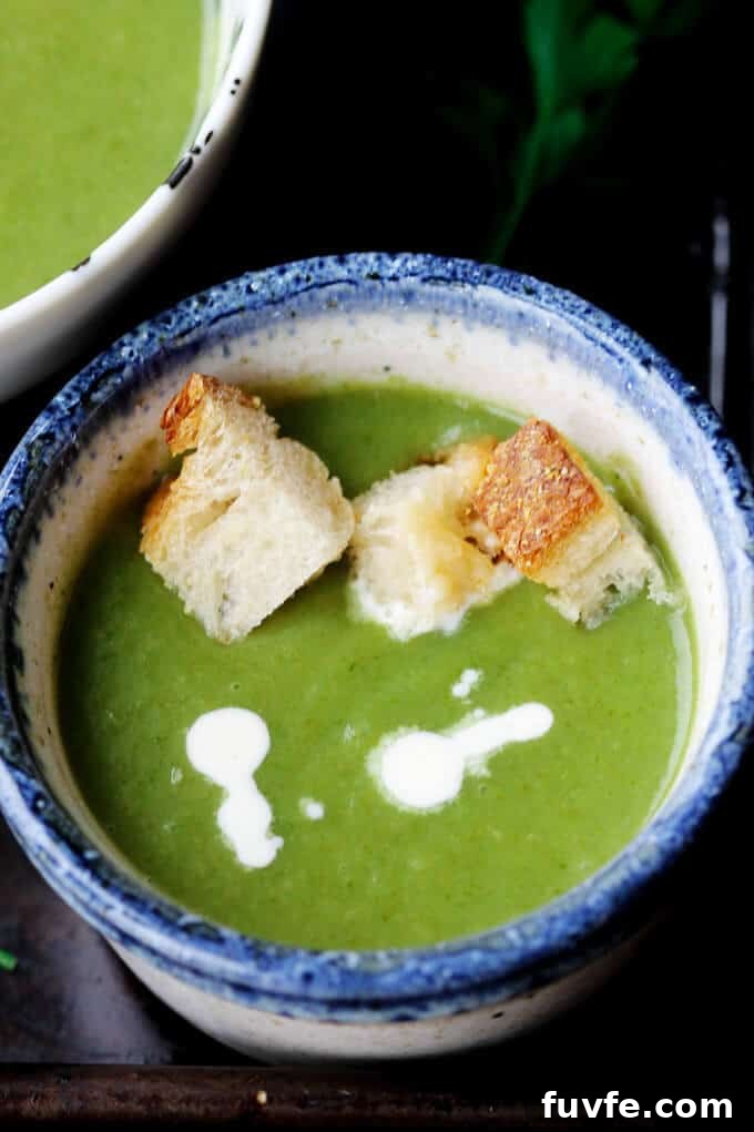 Creamy spinach soup with croutons and dollop of cream in a bowl
