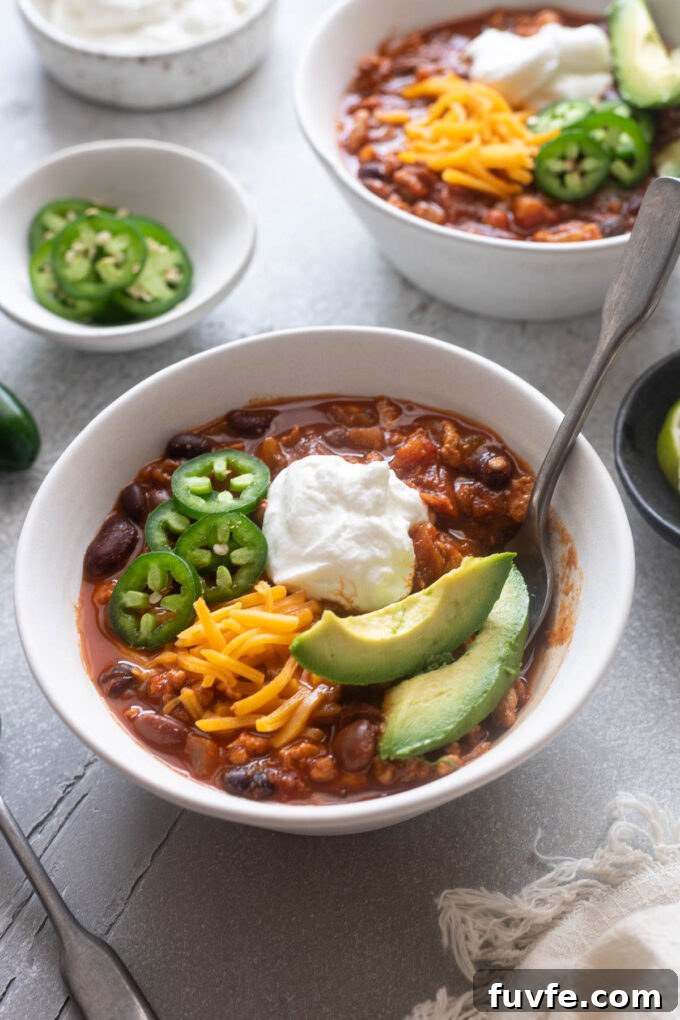 Bowl of ground chicken chili with a spoon digging in.