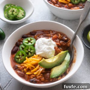 Bowl of ground chicken chili with a spoon digging in.