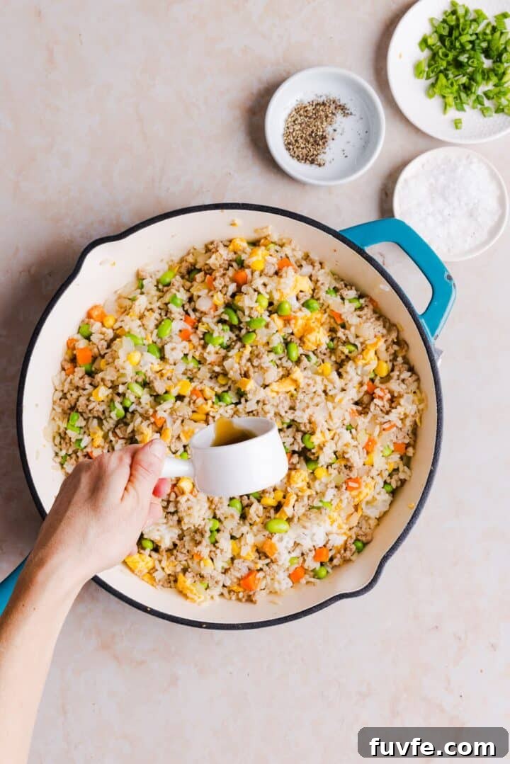 Savory Ground Turkey Fried Rice Recipe — Quick Weeknight Meal 11 Soy sauce being added to ground turkey fried rice in a large pan