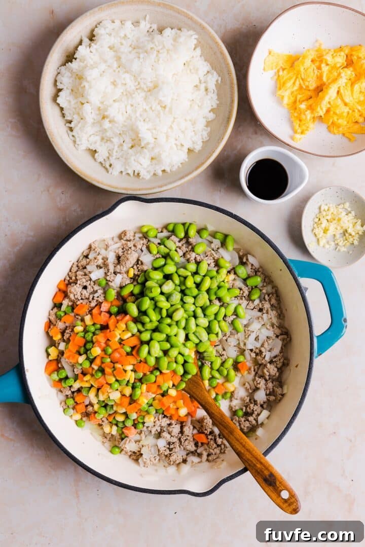 Savory Ground Turkey Fried Rice Recipe — Quick Weeknight Meal 8 Frozen vegetables added to a pan with cooked onions and ground turkey