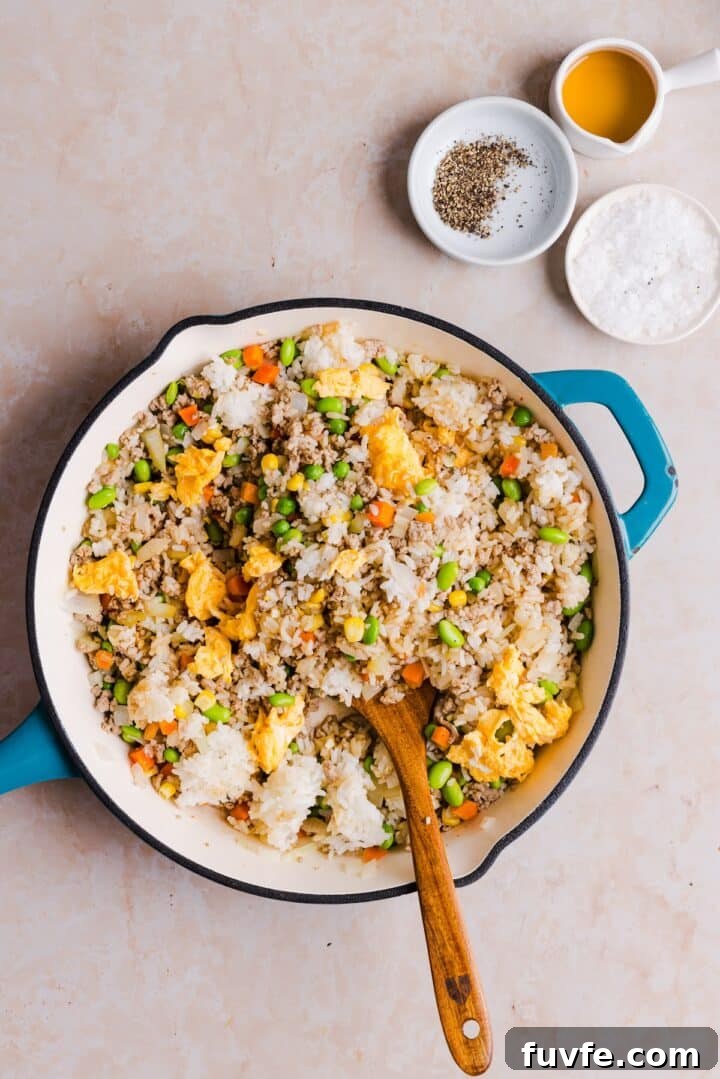 Savory Ground Turkey Fried Rice Recipe — Quick Weeknight Meal 10 Rice and scrambled eggs being added back to a pan with other ingredients for turkey fried rice