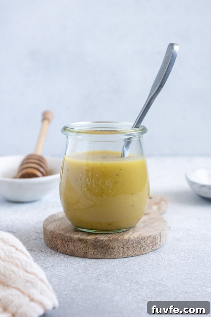 Homemade Honey Champagne Vinaigrette Recipe for Salad Dressing 3 Champagne vinegar dressing in a jar with a spoon inside.