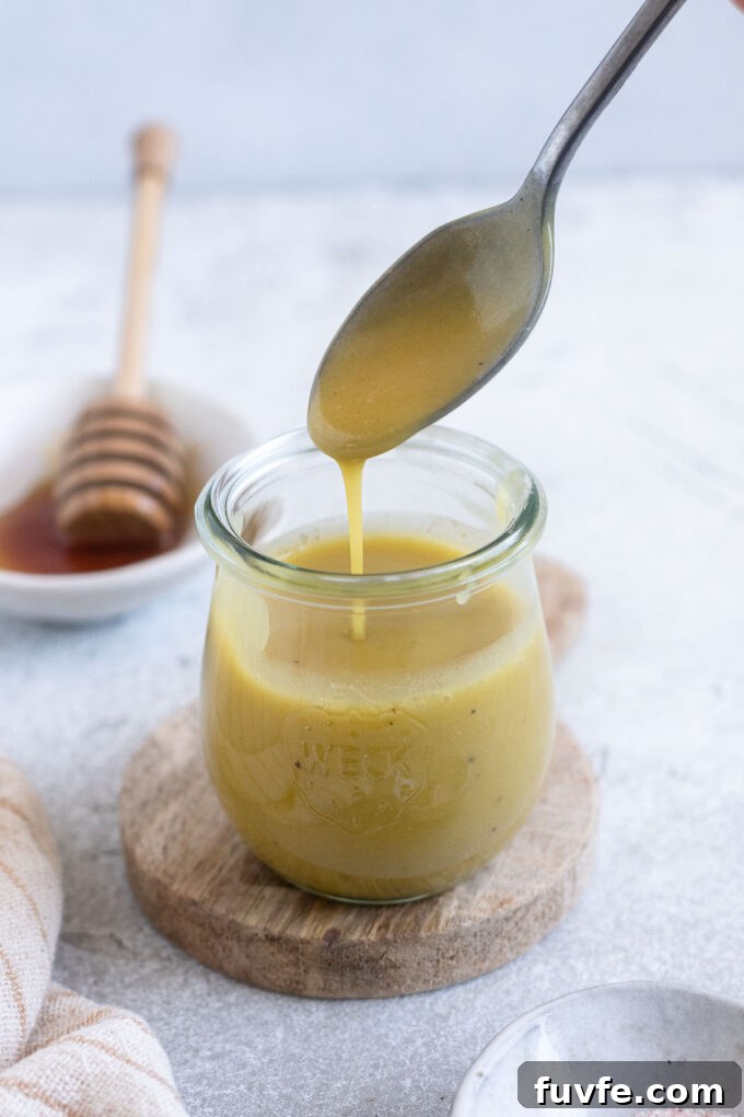Homemade Honey Champagne Vinaigrette Recipe for Salad Dressing 6 Champagne vinaigrette pouring into a jar from a spoon.