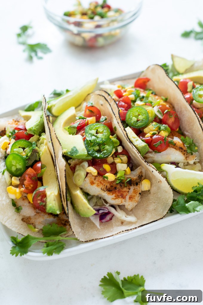 Grilled fish tacos on a plate with salsa, lime and cilantro