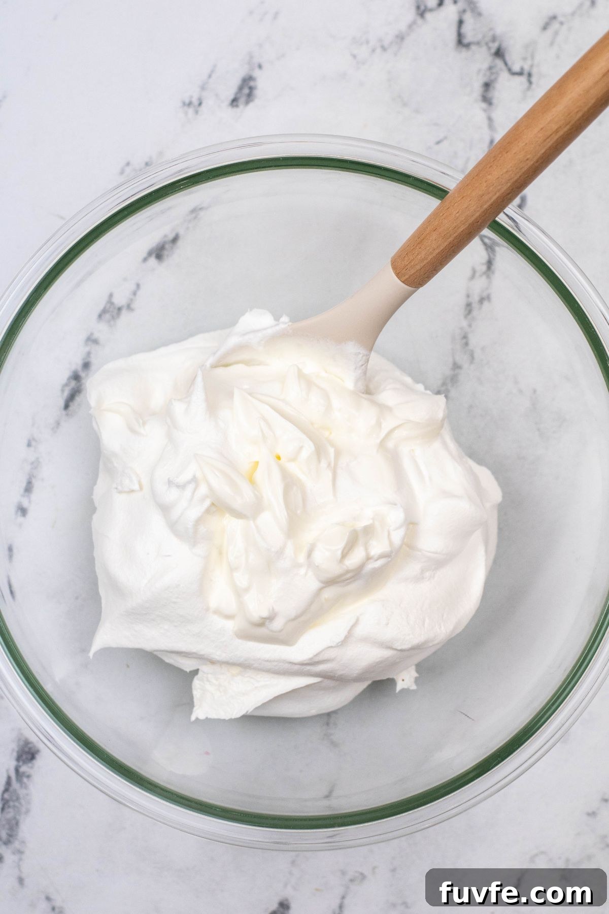 Whipped cream and sour cream, mixed together in a large clear glass bowl. 
