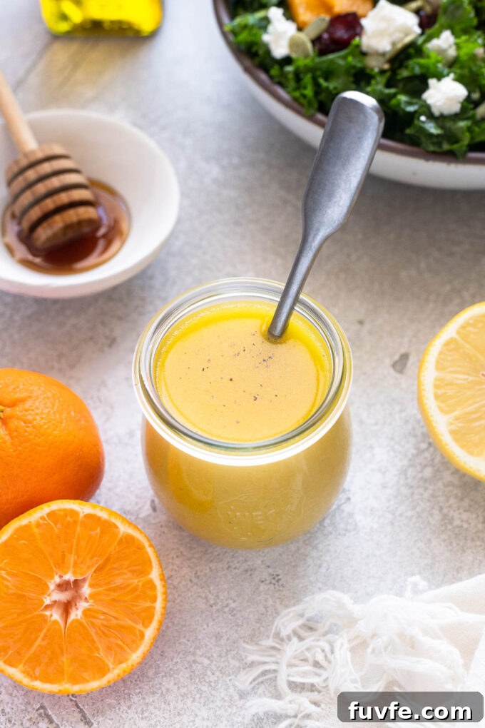 Orange salad dressing in a jar with a spoon inside.