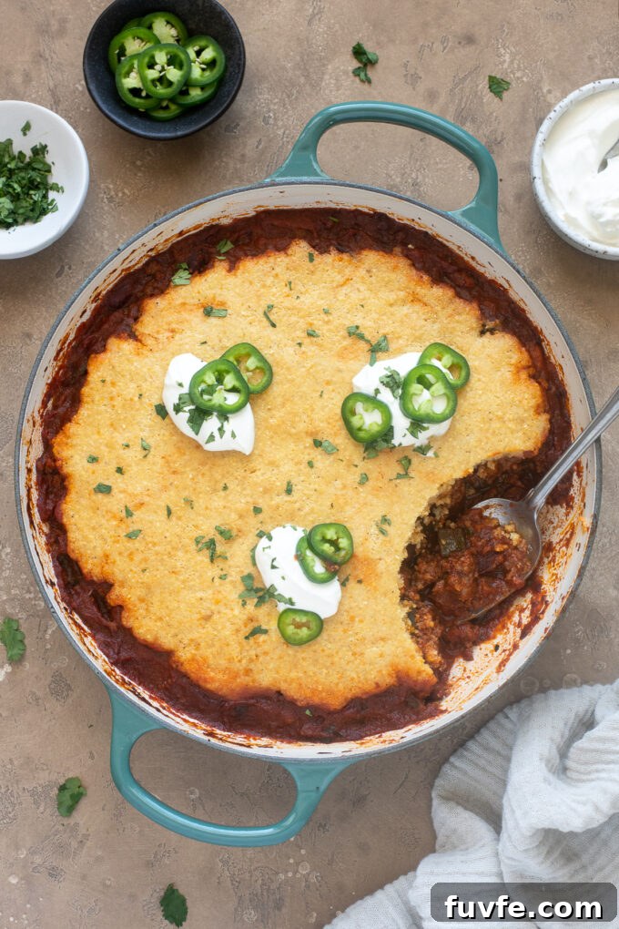 Cheesy Chili Cornbread Casserole Recipe 2 Chili cornbread casserole in pan with spoon digging in.