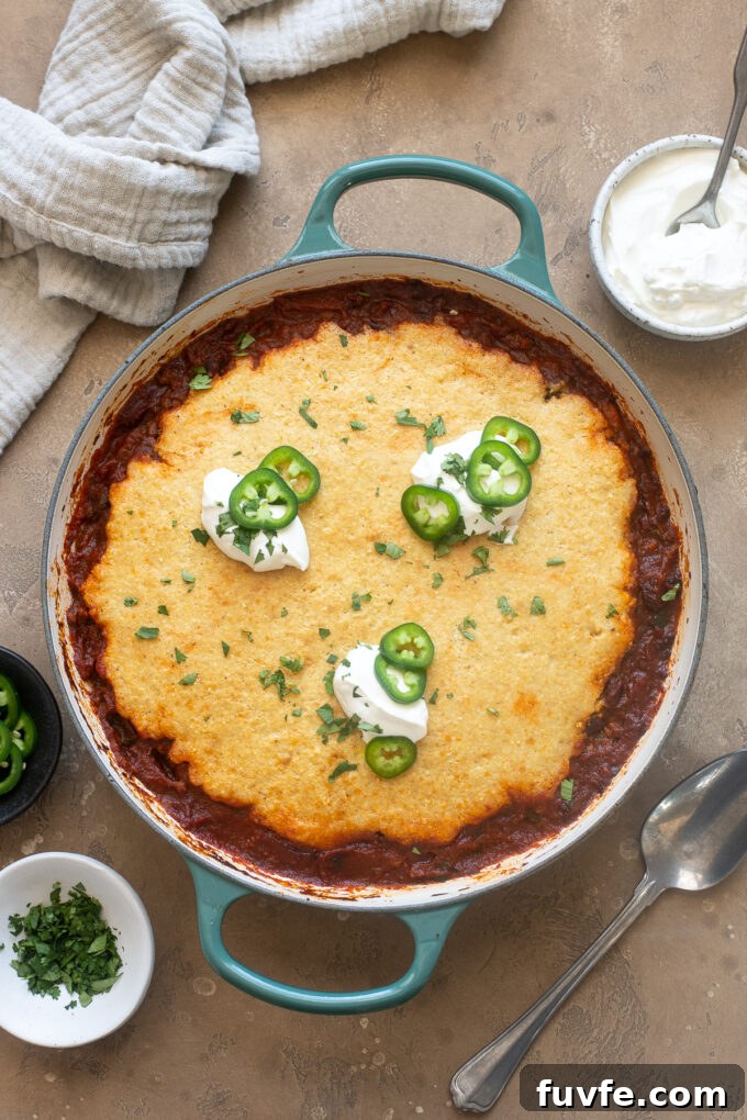 Cornbread chili casserole topped with sour cream and jalapeno.