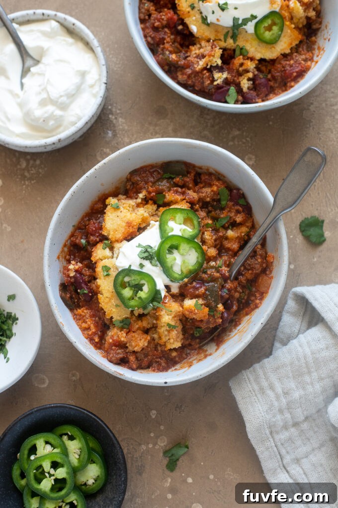 Cheesy Chili Cornbread Casserole Recipe 8 Chili casserole with cornbread in a bowl topped with sour cream.