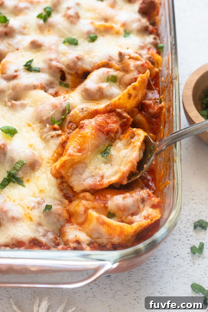 Baked Cheesy Ground Beef Stuffed Shells 2 Serving spoon with stuffed shells with ground beef.