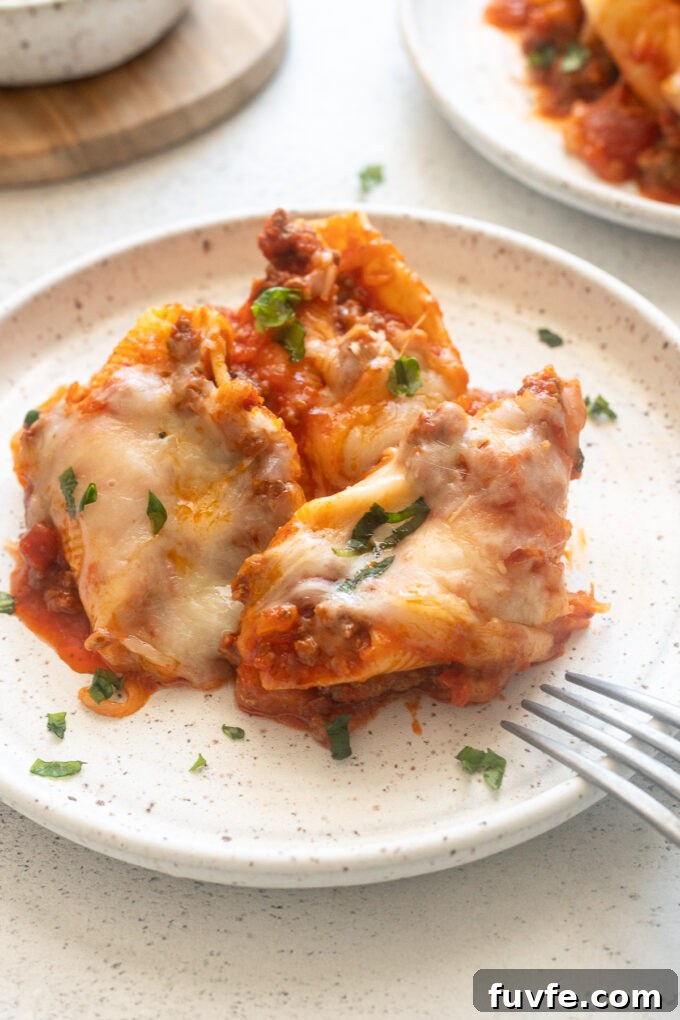 Baked Cheesy Ground Beef Stuffed Shells 7 Ground beef stuffed shells on a plate with fresh basil.
