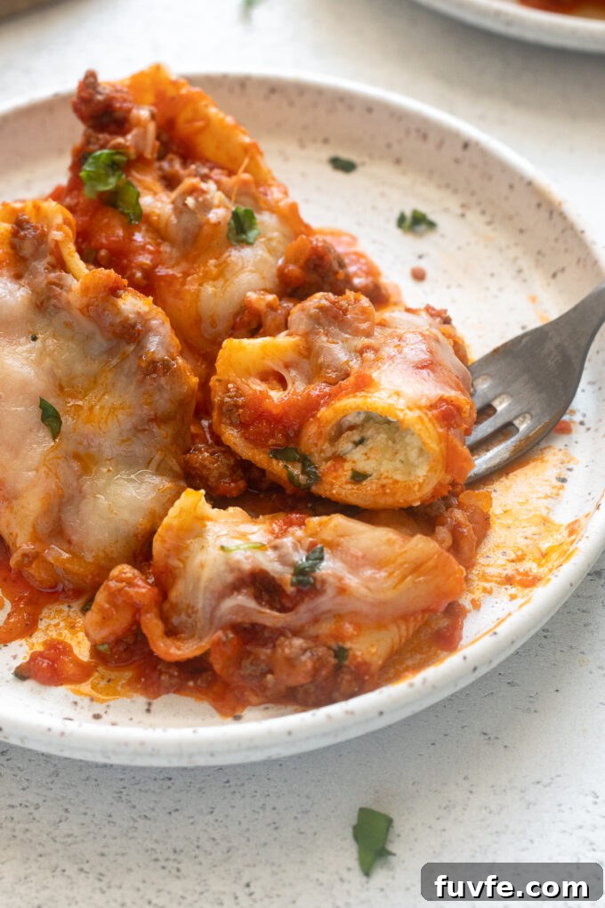 Stuffed shells with ground beef on a plate with a fork digging in.