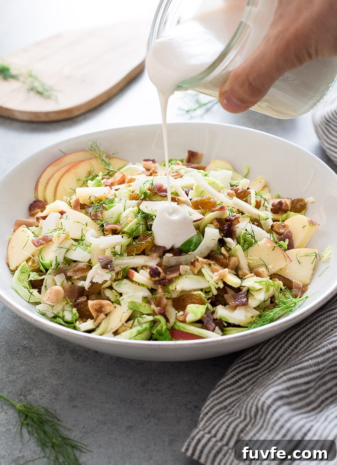 Shaved brussels sprout salad with dressing pouring over it