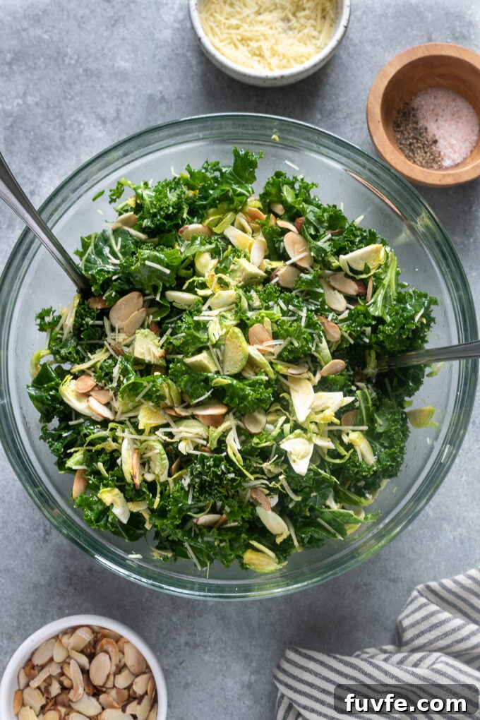 Crunchy kale salad with almonds and brussels sprouts in a mixing bowl.