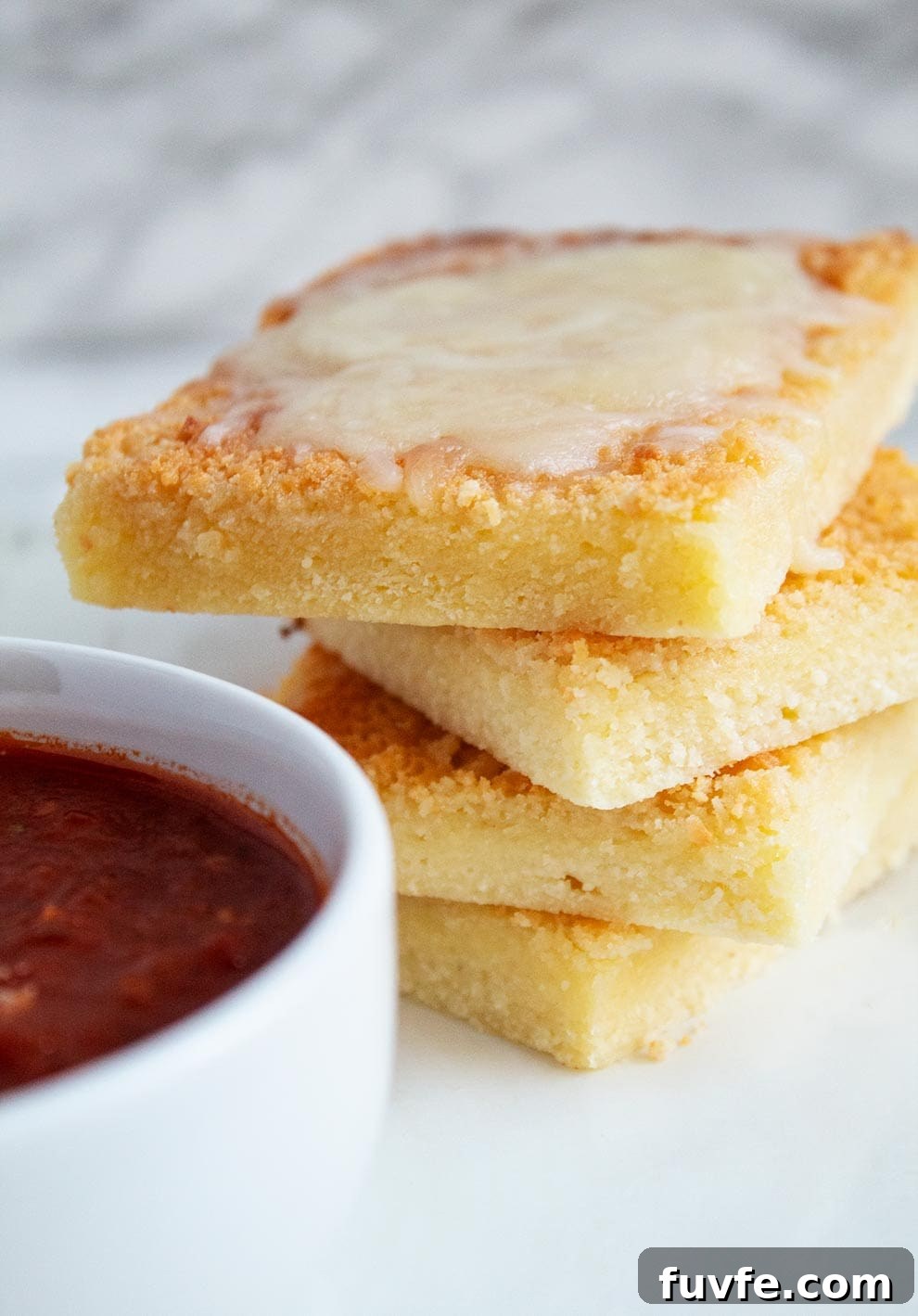 keto garlic flatbread on a white plate next to a white bowl filled with spaghetti sauce