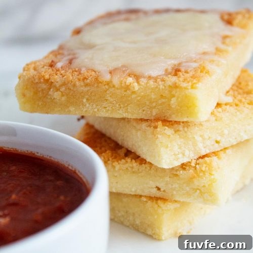 keto garlic bread on a white plate next to a white bowl filled with spaghetti sauce