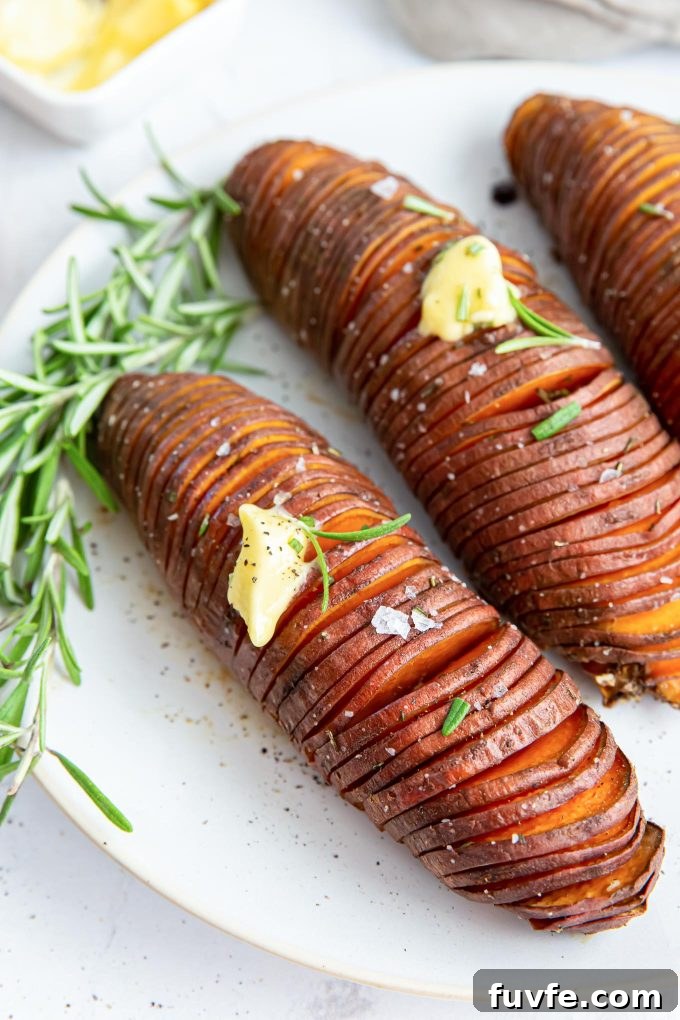 Hasselback sweet potatoes on a plate with butter and rosemary