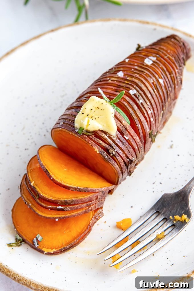 Rosemary hasselback sweet potato on a plate with butter on top