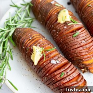 Hasselback sweet potatoes on a plate with butter and rosemary