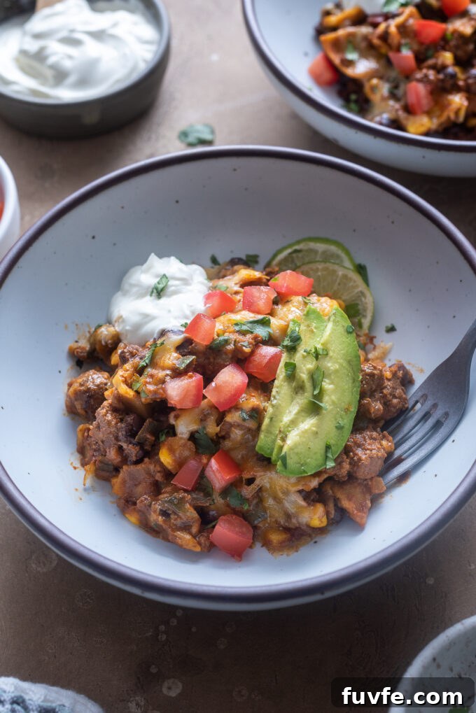 Cheesy Ground Beef Enchilada Casserole Recipe 9 Serving of skillet enchiladas in a bowl with tomato, avocado and sour cream.