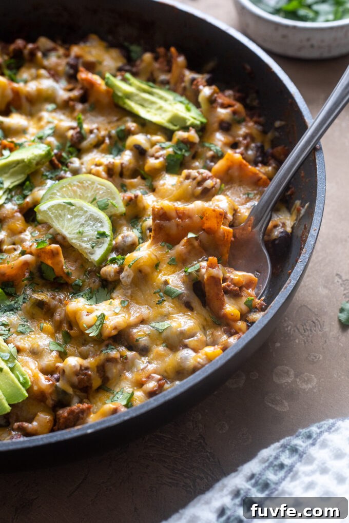 Cheesy Ground Beef Enchilada Casserole Recipe 7 Ground beef enchilada casserole with serving spoon digging into skillet.