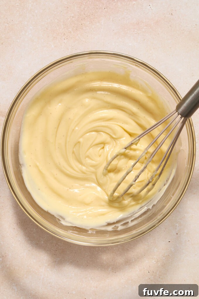 Silky Pastry Cream (Crème Pâtissière) Recipe 13 Homemade pastry cream in a mixing bowl with a whisk.
