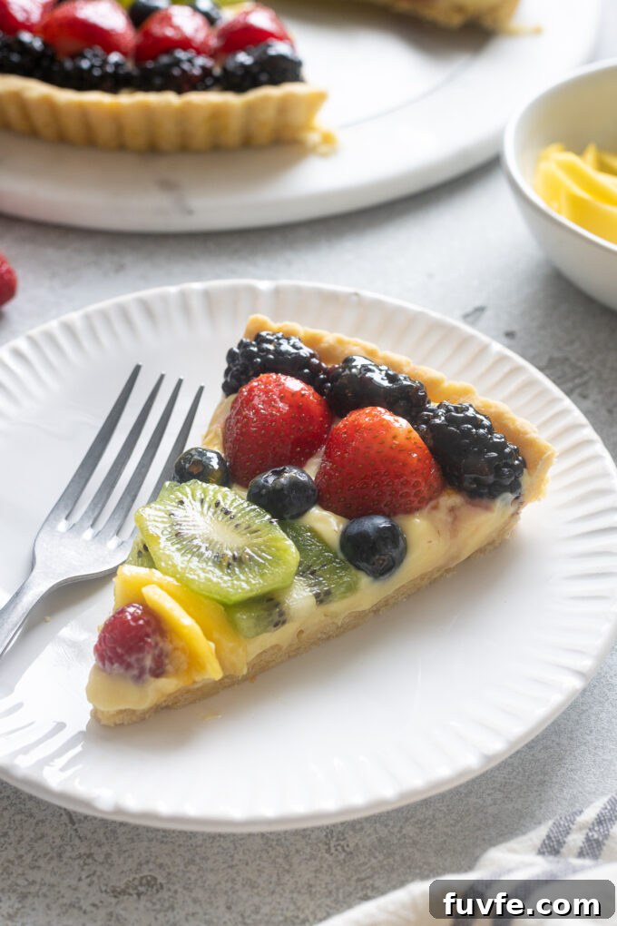 Slice of French fruit tart on a white plate.