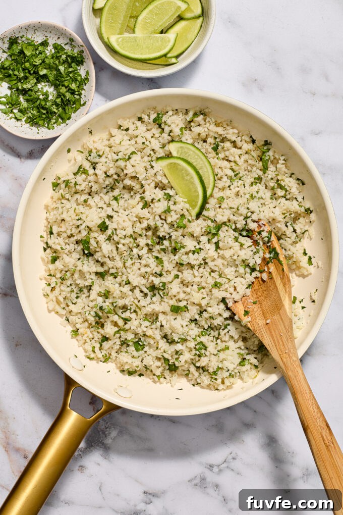 Cilantro lime riced cauliflower in a skillet with wooden spoon.