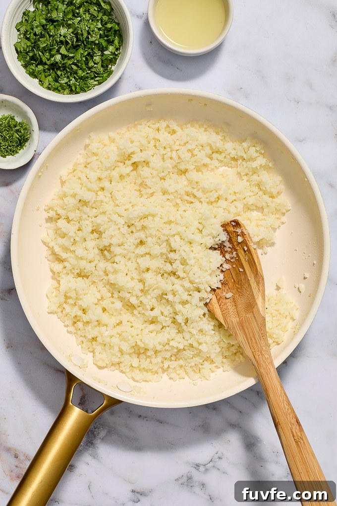 Cooked frozen riced cauliflower in skillet.