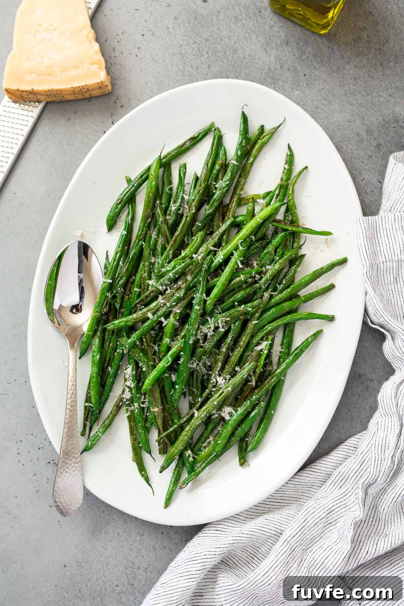 platter of roasted green beans with a spoon and linen