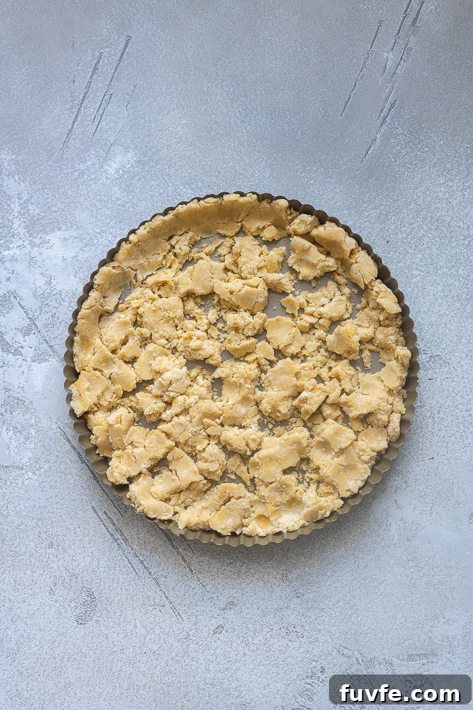 Chunks of pate sucree dough in tart pan.
