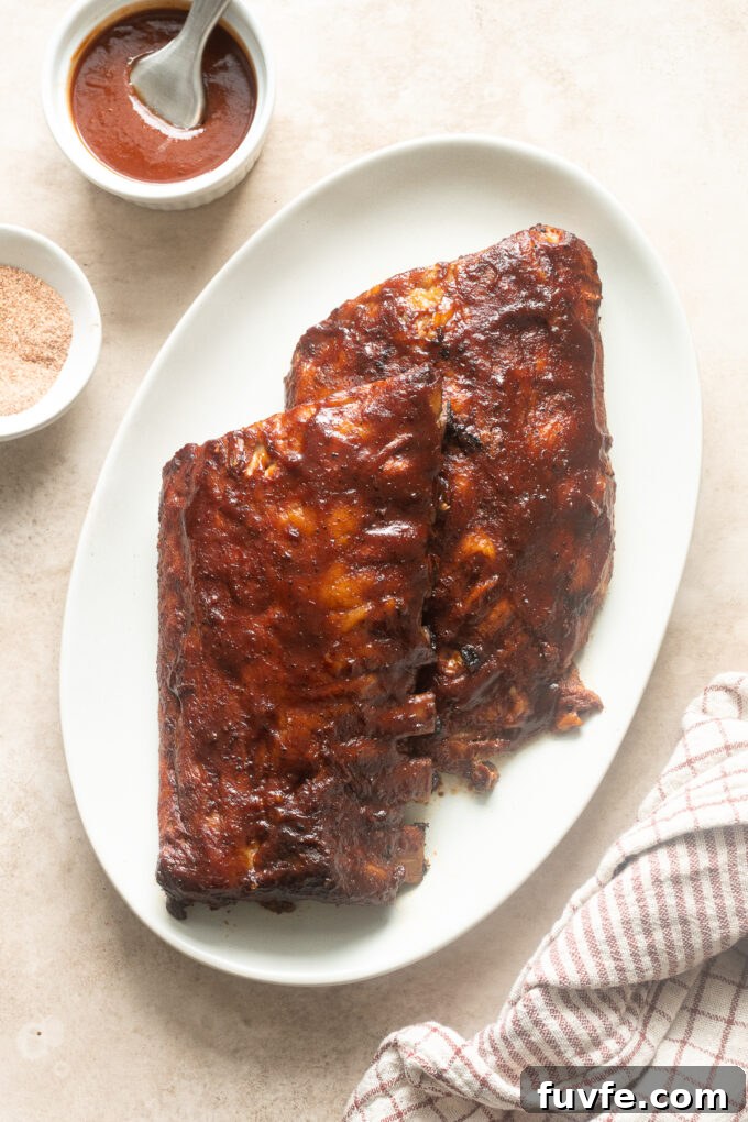 Fall-Off-the-Bone Slow-Cooker Baby Back Ribs 2 Slow cooker babyback ribs on a platter smothered in barbecue sauce.